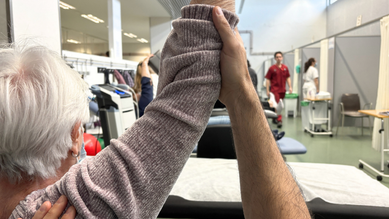 primer plano de señora mayor con brazo levantado por el fisioterapeuta
