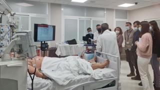 grupo de personas con bata blanca al lado de una cama de hospital con muñeco simulan una prueba