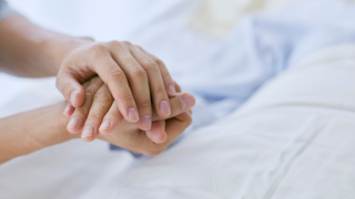 Mano que coge la mano de alguien en una cama