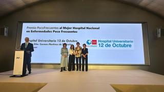 Cuatro personas en un escenario con un premio
