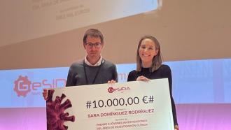 Retrato de Sara Domínguez Rodríguez a la derecha con otra persona, un hombre a la izquierda y ambos detrás de un gran diploma, en un escenario, donde pone 10.000 euros