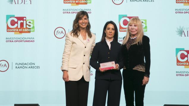 Tres mujeres en un escenario la del medio con un premio