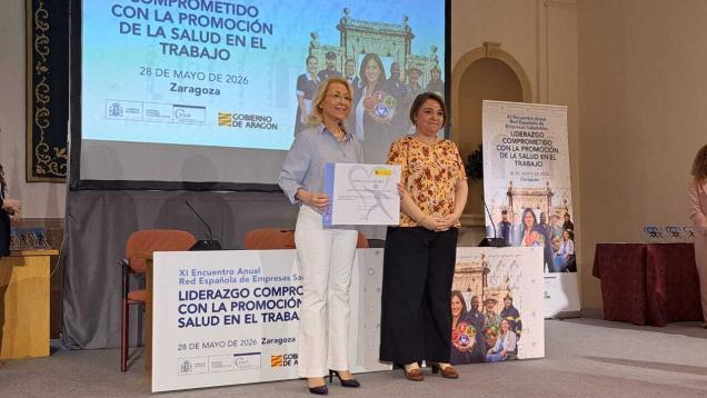 Señora posando con un diploma en escenario con otra señora