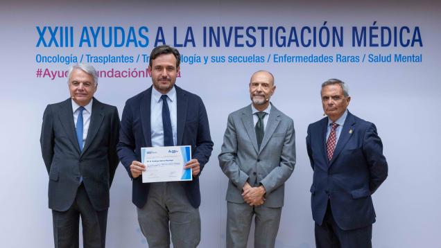Cuatro hombrees posando el del medio a la izquierda con un diploma los otros un paso atrás