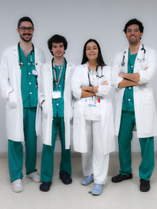 grupo de cuatro médicos con bata, tress hombre y una mujer en el centro