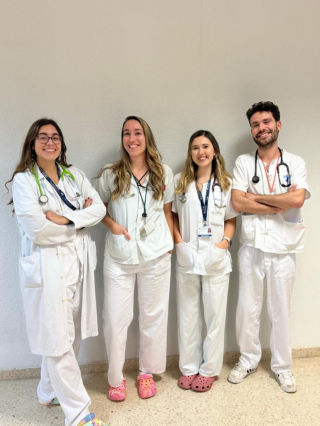 grupo de cuatro médicos con bata, tres mujeres y un hombre a la derecha