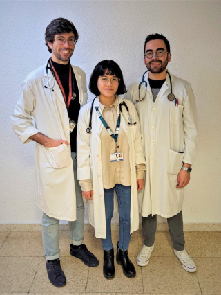 tres médicos con bata posando, dos hombres y en el medio una mujer