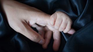 Mano de bebé agarrando mano adulto