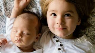 dos niños pequeños sobre una sábana sonriendo