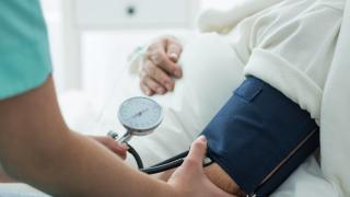 profesional de enfermería tomando la tensión a una persona en la cama