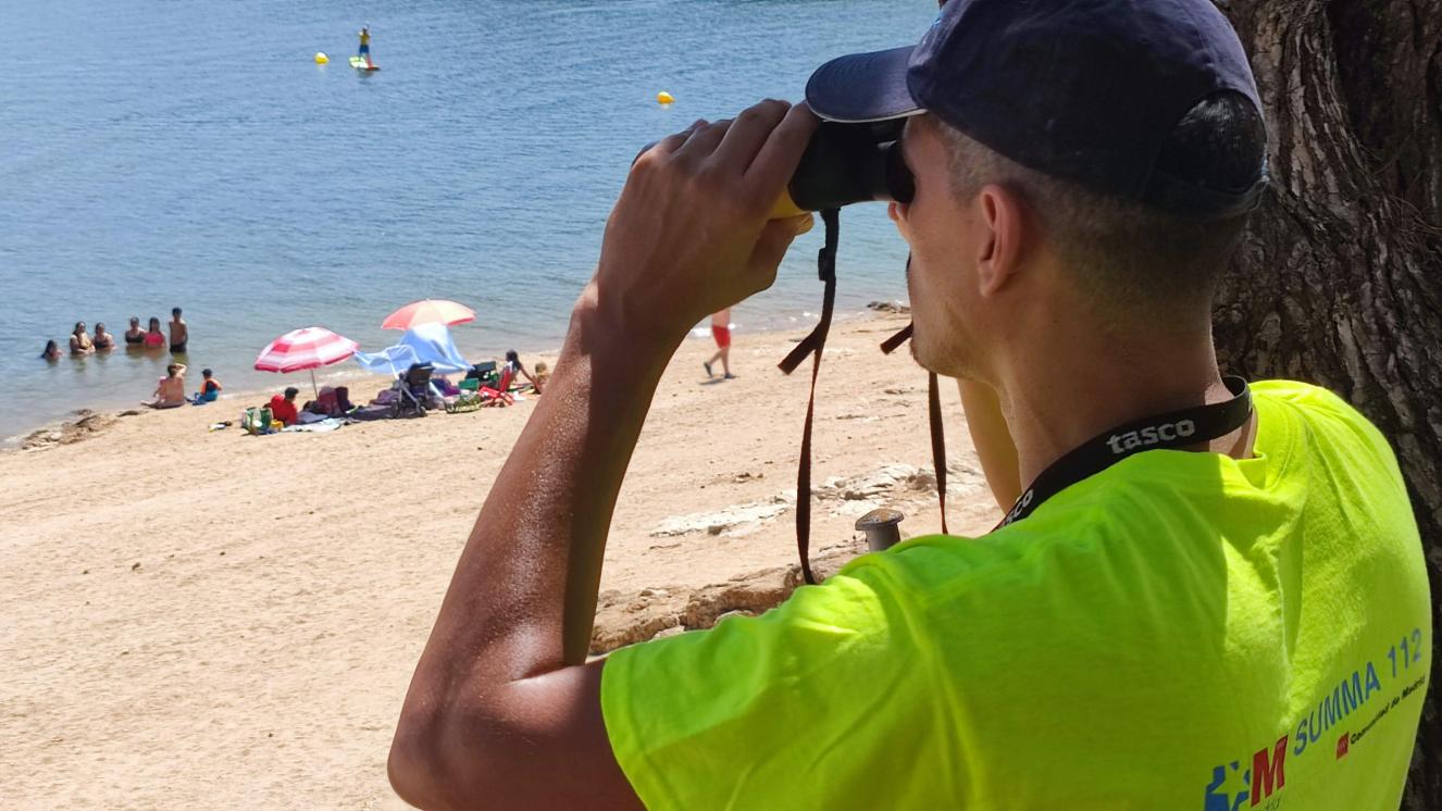 Técnico en Emergencias Sanitarias - Socorrista vigilando con los prismáticos la zona de baño de la Playa Virgen de la Nueva desde la base del Dispositivo del SUMMA 112 en el Pantano de San Juan 