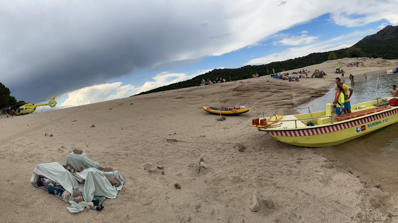 Lancha rígida de rescate del SUMMA 112 en el Pantano de San Juan con los Técnicos del SUMMA 112 a bordo de la misma en la orilla de la Playa Virgen de la Nueva del Pantano de San Juan y el Helicóptero del SUMMA 112 despegando  