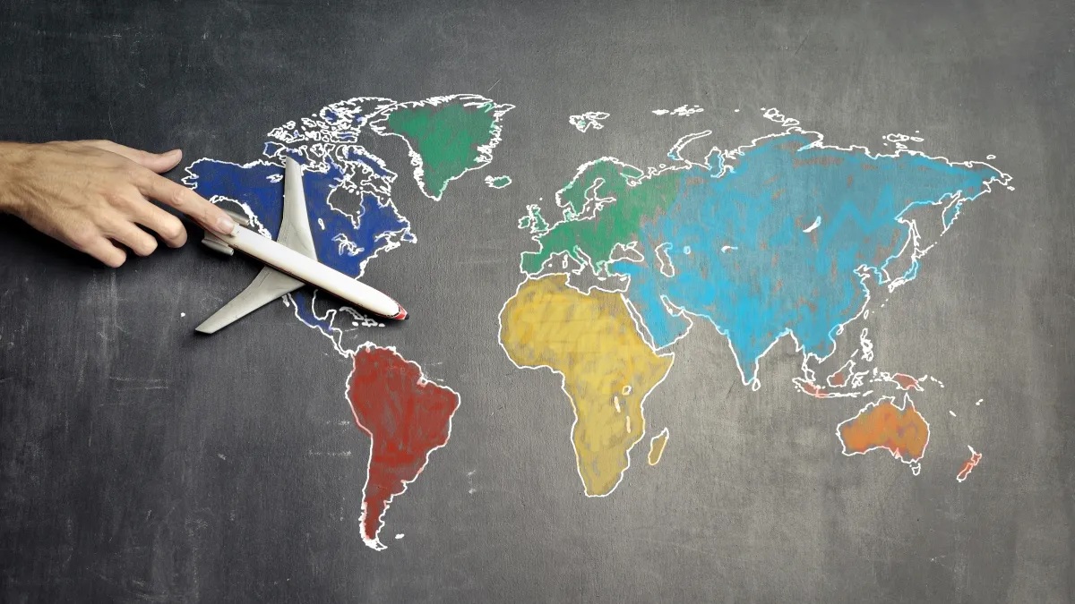 Pìzarra con un mapa mundial y un avión dirigido con una mano