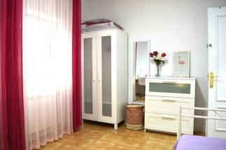 Habitación espaciosa para una persona, luminosa con mobiliario de estudio, de almacenamiento y cama individual.