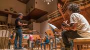 Clase de música en el auditorio de un conservatorio de música. Un grupo de jóvenes guitarristas escuchan a su profesor sobre el atril