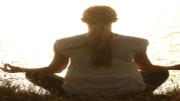 Mujer meditando sentada mirando al sol