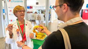 Una mujer entrega una pieza de fruta a un joven en la puerta de un hospital