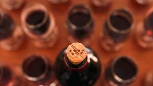 Botella de vino con un tapón de corcho con el símbolo de la Comunidad de Madrid rodeado de copas de vino