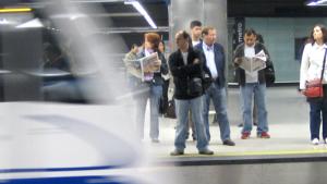 Personas esperando en andén mientras el metro entra en la estación