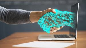 Una persona da la mano a otra digitalizada que sale de una pantalla