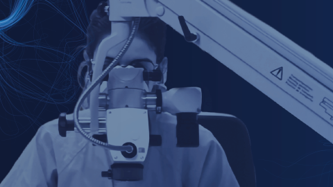 Imagen de una persona con indumentaria de centro hospitalario mirando a través de un microscopio