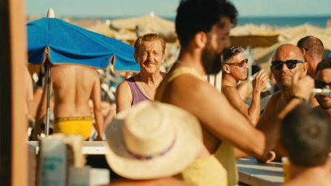 Fotograma que muestra un hombre en una playa abarrotada de personas y sombrillas