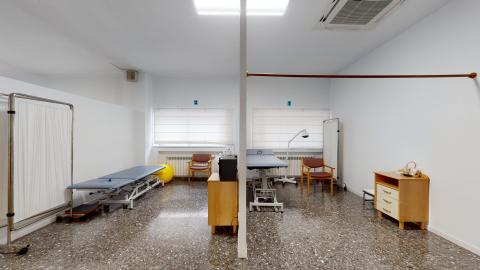 Fisioterapia. Dos espacios diferenciados con camillas de fisioterapia. Al fondo ventanas con cortinas blancas traslúcidas.