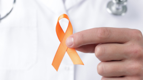 Esclerosis múltiple mano de doctor cogiendo un lazo naranja
