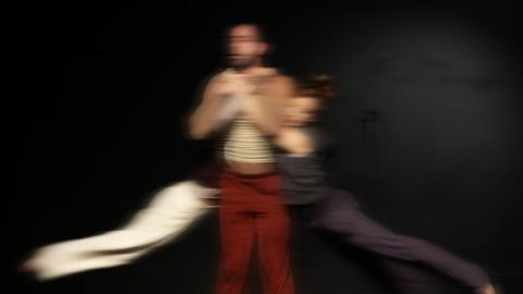 fotografía de escena, muestra un hombre, de cada brazo cuelga una mujer oscilando.