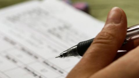 Formulario con una mano sosteniendo una pluma estilográfica