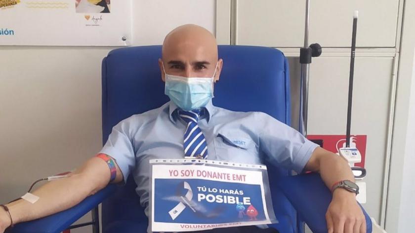Trabajador de la EMT donando con un cartel de apoyo a la donación