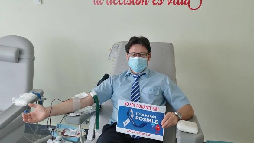 Trabajador de la EMT donando bajo un lema de la pared: Dona sangre de corazón