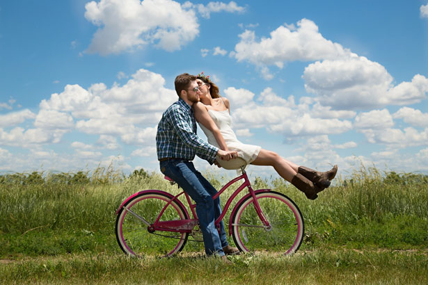 Pareja montada en una bicicleta en actitud cariñosa