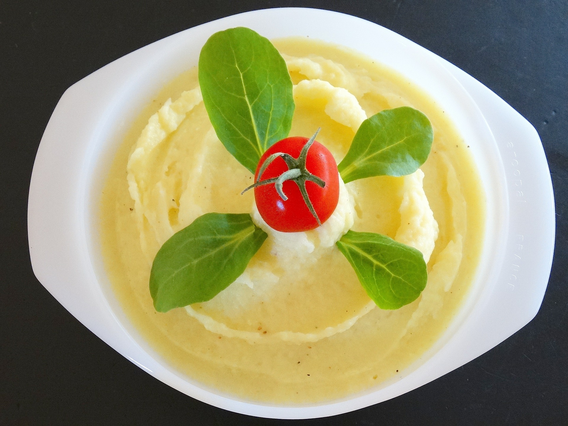 plato de puré de patatas con hojas de espinaca y tomate cherry