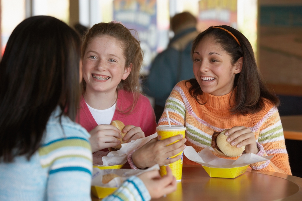 tres adolescentes comiendo en un restaurante