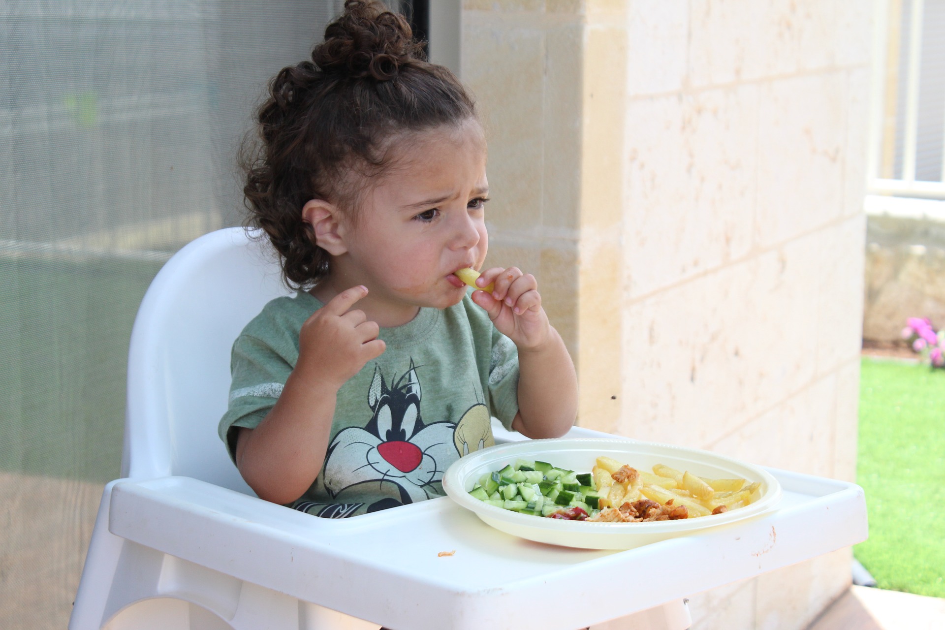 niña en trona comiendo con las manos