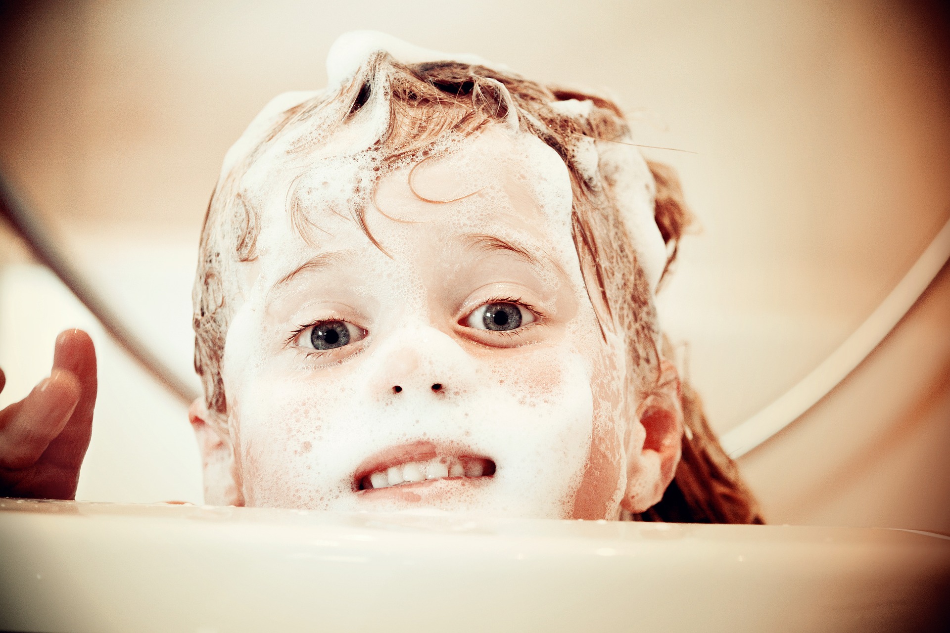 niña en el baño con la cara llena de espuma