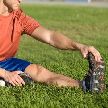 Deportista estirando sentado en la hierba