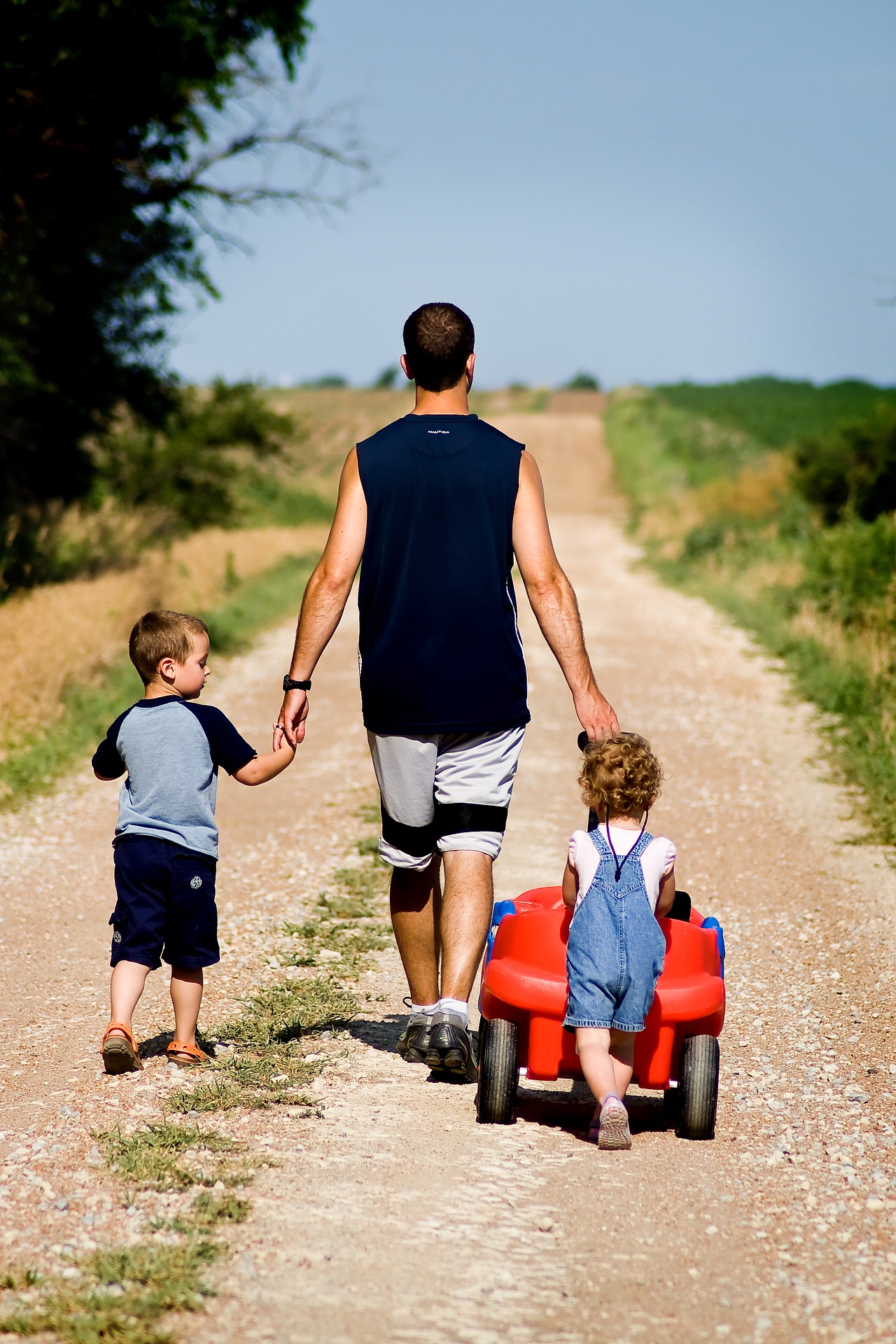 padre con dos hijos de espaldas caminando