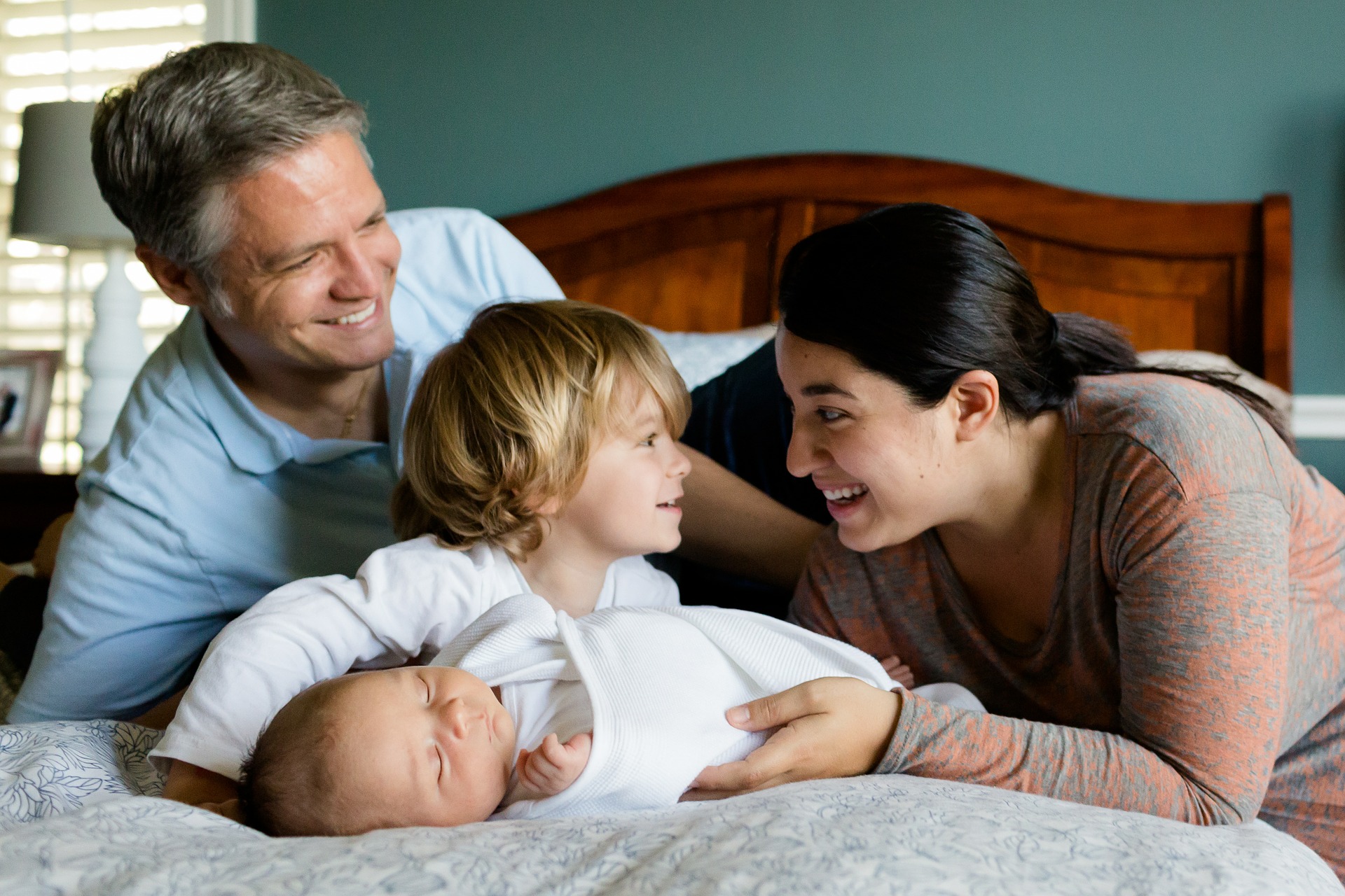 bebé dormido sobre la cama con padres y hermano