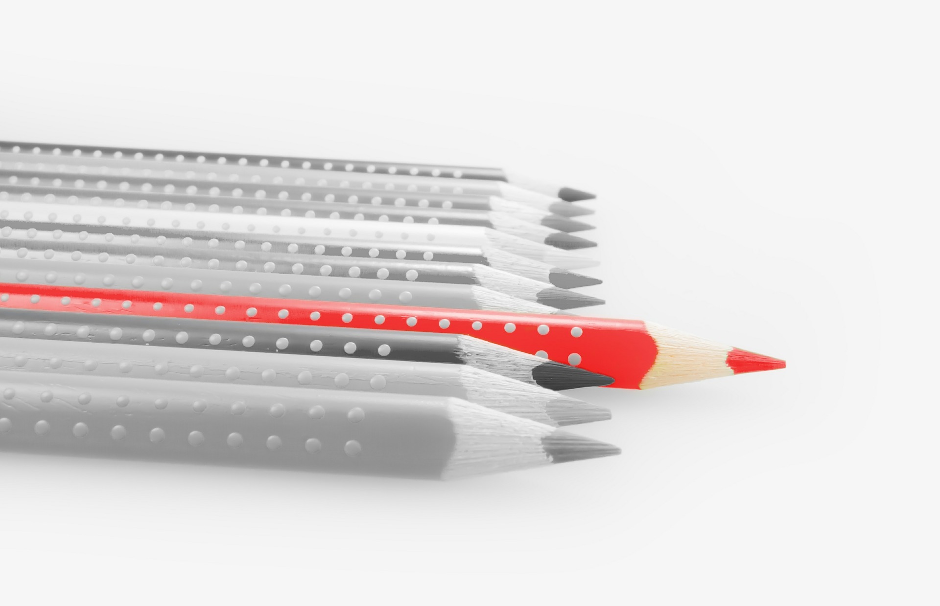 Fila de lápices con lápiz rojo sobresaliendo