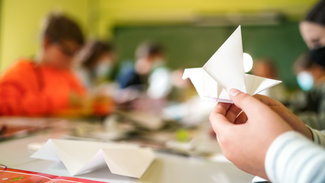 Las manos de un niño haciendo una pajarita de papel