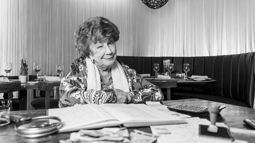 Mujer mayor sentada en una mesa con libros de contabilidad