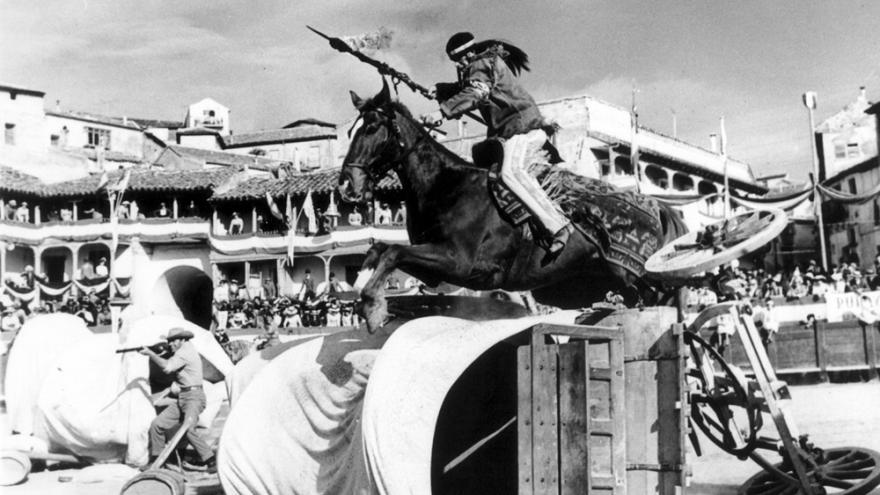 Indio a caballo saltando por encima de un carruaje volcado en el suelo