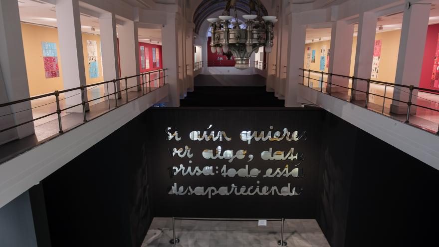 Vista de una sala de exposiciones con unas letras hechas con espejo