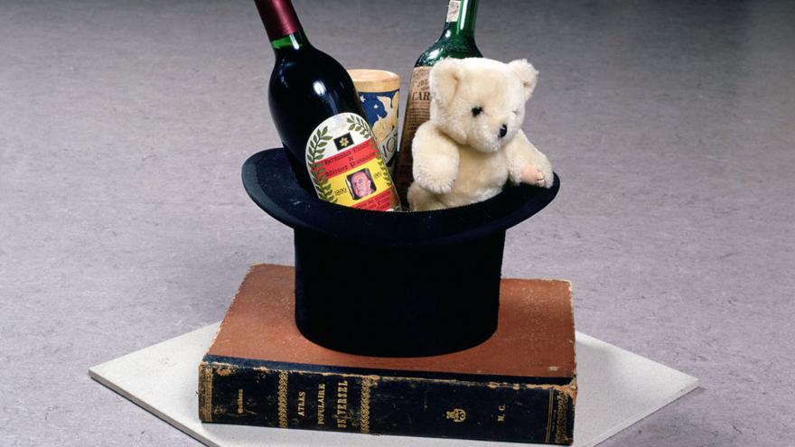Sombrero con 2 botellas y un osito de peluche sobre un libro