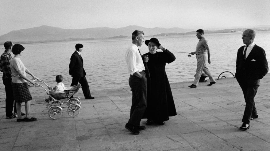 Families, priest and other people strolling on a pier