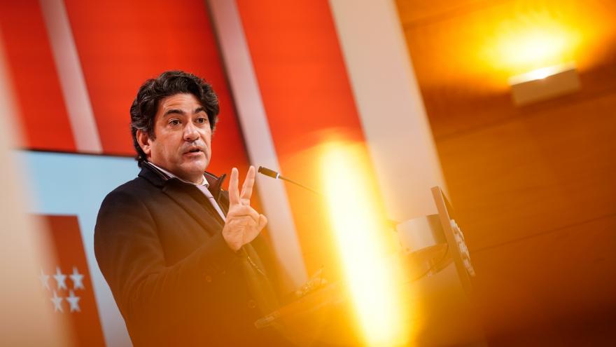 El consejero explicando las propuestas en el atril y detrás de una luz desenfocada