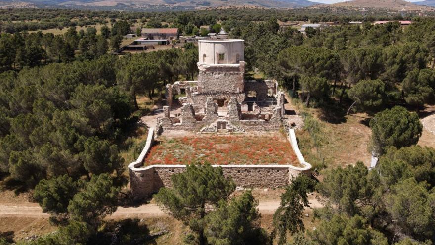 edificio con un torreón semicircular rodeado de un pinar y un campo de amapolas