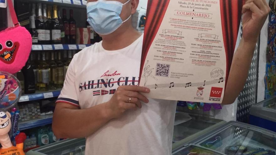 comerciante mostrando cartel de "El comercio a Escena"